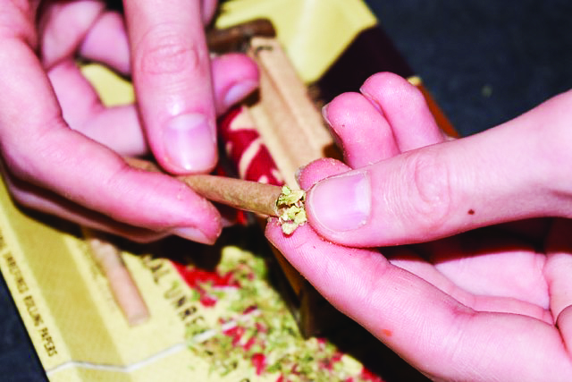 Campus life often glorifies substance use, something that may lead to addictions. Closeup of someone rolling a blunt. [Photo by Spencer Colby]