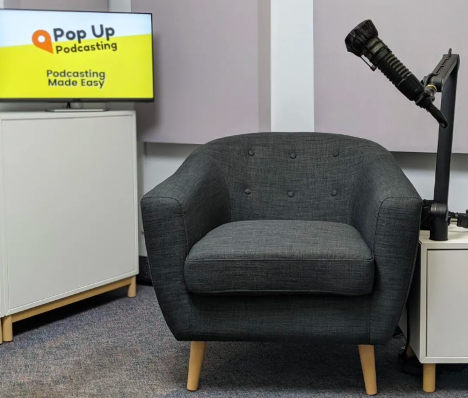 A photo of a chair by a screen that says Pop Up Podcasting.