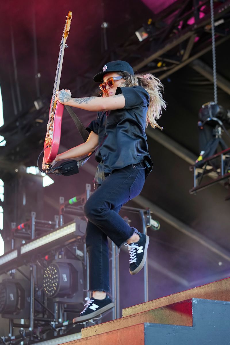 Tash Sultana performs at Bluesfest. She jumps in the air holding her electric guitar.