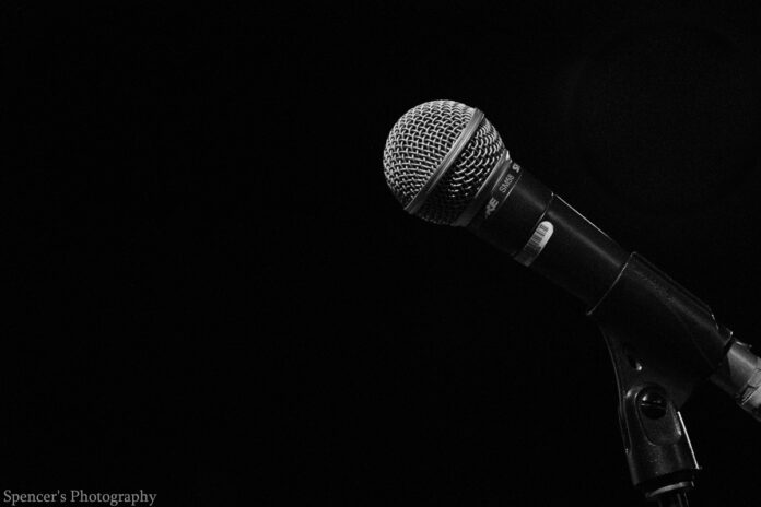 A microphone is pictured behind a black background.