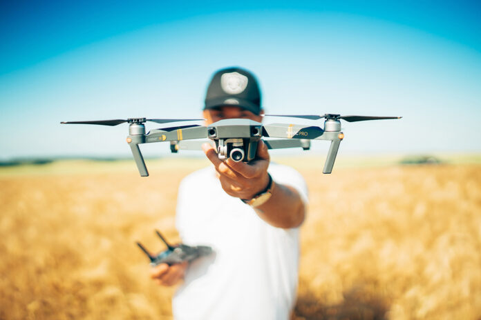 A person is pictured holding a drone in a field.