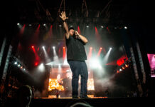 Review of Bluesfest Day Three: Buzzing with life and energy Luke Combs performs at Bluesfest. He sings into the microphone with his hand raised in the air.