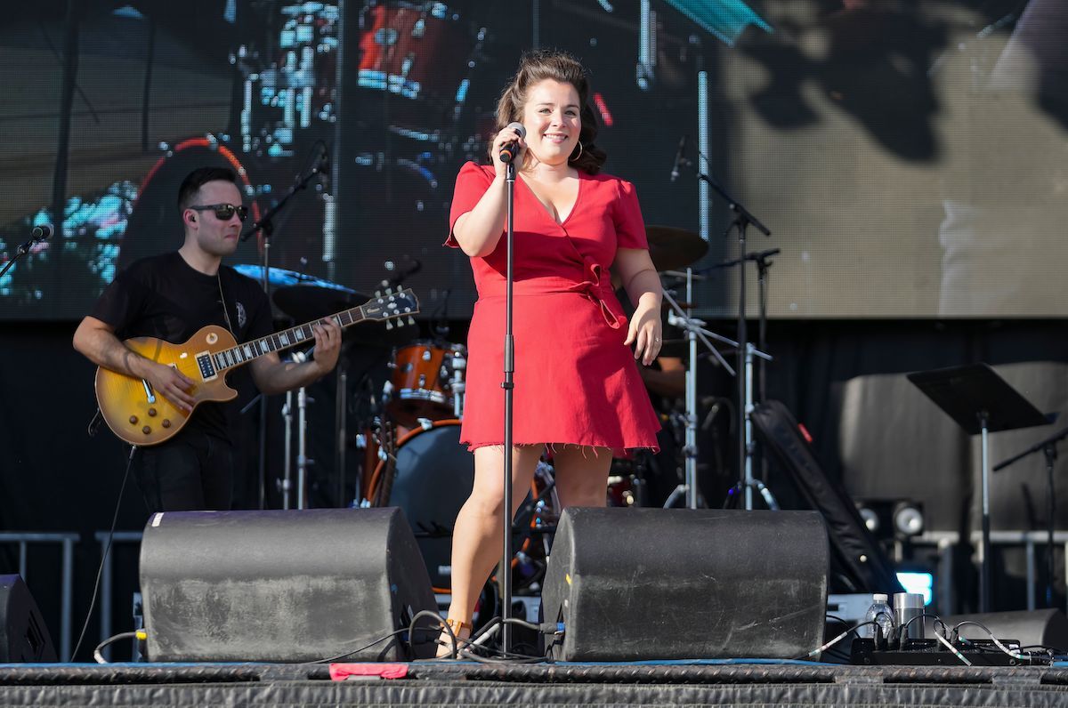Mack & Ben perform at Bluesfest. Mack is holding her microphone stand and smiling to the audience.