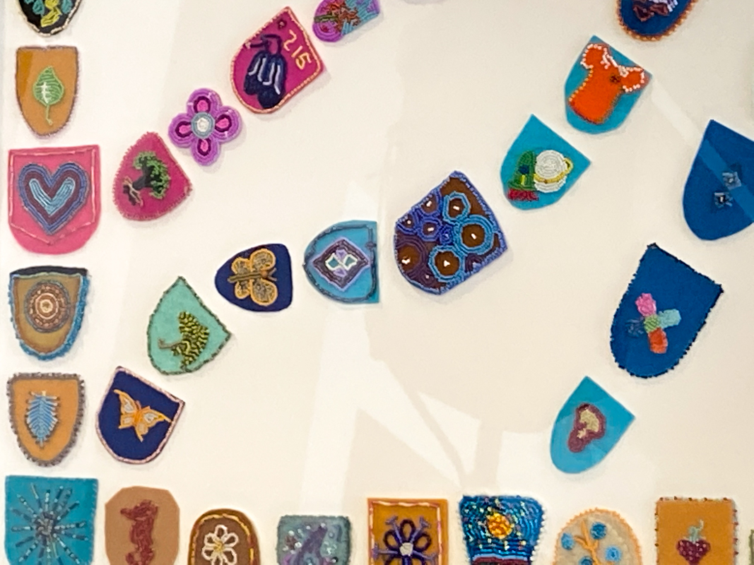 Colourful beaded baby vamps are on display, scattered along felt and leather backgrounds.