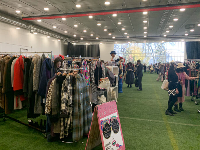 Tables and booths line the inside of Carleton University's Fieldhouse, selling items such as vintage clothes and antique jewelry.