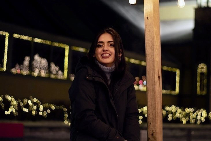 Sahar Shoaib sits outside in a darkly lit space with twinkle lights in the background