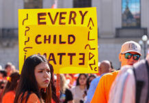 In Photos: Healing and learning at Canada’s third National Day for Truth and Reconciliation People wearing orange shirts standing below yellow signs that read "Every Child Matters."