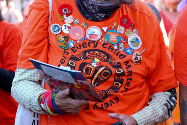 Close up of a person wearing an orange short adorned with stickers.