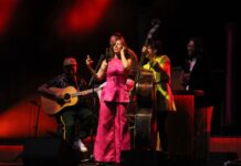 Review: Lake Street Dive is undeniably ‘Good Together’ at Ottawa Jazz Festival Lake Street Dive main singer in a pink power suit, hold the mic and sings on stage with her band.
