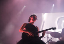 Review of CityFolk Day One: The Beaches breathe life into Canadian alt-rock scene Women wearing all black with black sunglasses kneels on stage and strums her guitar hard amidst red lighting.