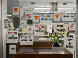 On a glass window, around 20 posters speaking to Indigenous issues for National Day of Truth and Reconciliation are displayed.