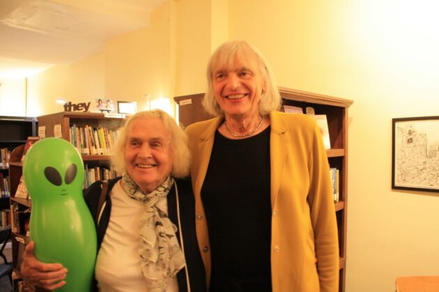 Two woman smile next to each other in a library