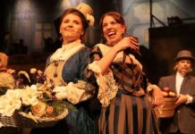 Review: Paper Moon Theatre’s ‘Sweeney Todd’ is half-baked amid technical flaws Two women of the ensemble, one in a blue 1700s dress the other in a brown and black 1700s dress.