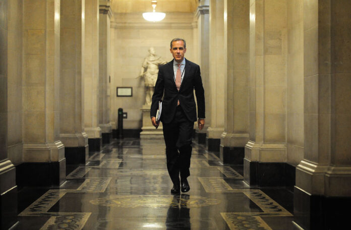 A man in a suit walks down a hallway.