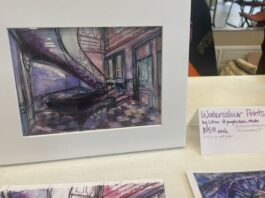 On a white display table, a purple watercolour of an architecture building is displayed with a sign that reads "Watercolour prints."