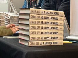 Copies of Carol Off’s new book, 'At A Loss For Words: Conversation in the Age of Rage,' sit on a table at Southminster Church in Ottawa. The spines of the books are all piled up on top of each other with a hand reaching out to sign a copy.