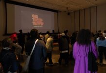 New dance battle puts spotlight on Ottawa’s hip-hop community In a dark room, there is a crowd of people. On a projector, it reads "oh that's tight" in all caps.