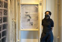 Gallery 101’s ‘Do Weeds Still Grow in Heaven?’ confronts abuses in queer and trans relationships A women wearing all black with a black mask, stands to the right of an all white textile art piece.