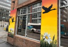 Paint It Up! offers creative outlet to youth experiencing homelessness Wrapped around a brick building, a mural of a sunset depicting a geese flying over head is painted. There are also flowers (like daisy's) on the bottom of the mural
