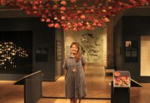 ‘Rewilding’ exhibit showcases artists’ kinships with the natural world In a gallery room, a woman stands in front of her pink crocheted flowers display