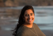Carleton researcher to study EDI policies at Ottawa universities A woman with brown hair and dressed in a brown shirt smiles at the camera against a beach background.