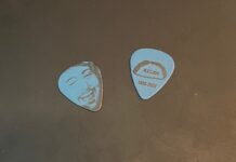 Remembering Riley: Community fundraiser concert keeps Ottawa musician’s legacy alive Two light blue guitar picks against a black table background. The left pick shows a sketch of Taylor’s face, while the right pick shows his nickname, “Riles,” on a taco with his date of birth and death.