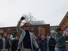 Young man raises his fist after winning a lookalike contest.