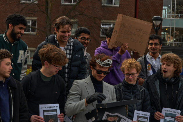 A crowd of young men watching someone open a gift box