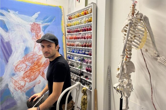 Adrian Gor sits in his studio, where he makes oil painting prints and pastel drawings, on Jan. 18, 2025. His latest exhibit ‘Retold Prototypes Without A Story’ challenges ideals of masculinity through art. [Photo by Thuy Anh Nguyen/The Charlatan]