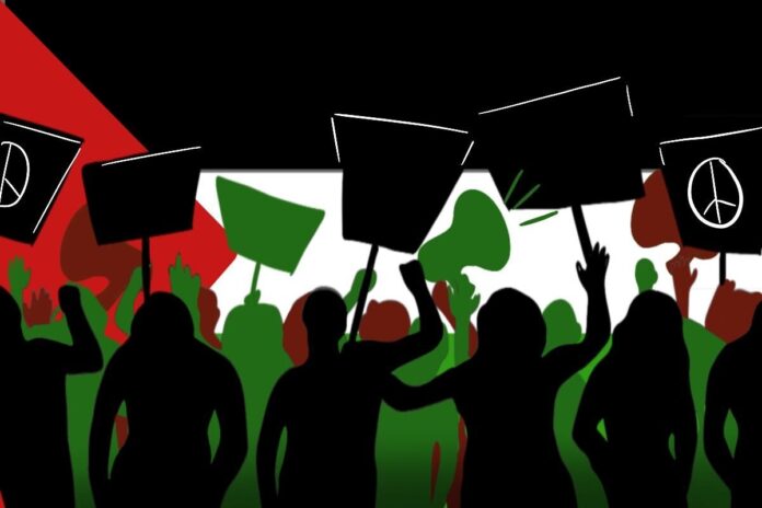 Silhouettes with signs standing in front of the Palestinian flag.