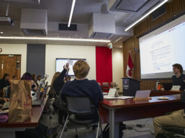 Students in chairs facing a podium at the front of the room.