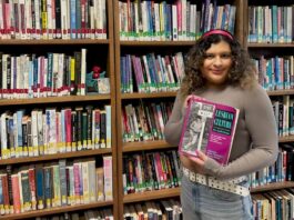 Person holds a book in front of a queer library