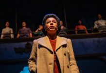 Review: NAC’s ‘Controlled Damage’ unravels the person behind the face of our $10 bill Woman stands on stage in brown trenchcoat
