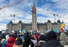 A group of protesters stand outside the Parliament Buildings in winter months.
