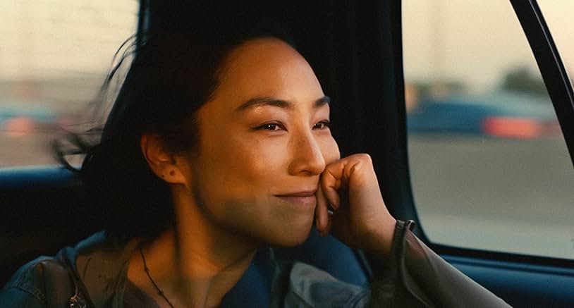 A woman sits in the back of a car and stares out of the window.