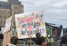 A colourful protest sign depicting a uterus and reading "Not your body, not your choice" is held up by a protester at Parliament Hill in downtown Ottawa.