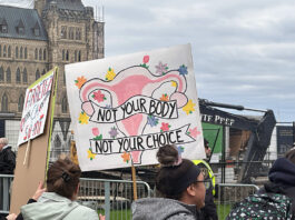A colourful protest sign depicting a uterus and reading "Not your body, not your choice" is held up by a protester at Parliament Hill in downtown Ottawa.