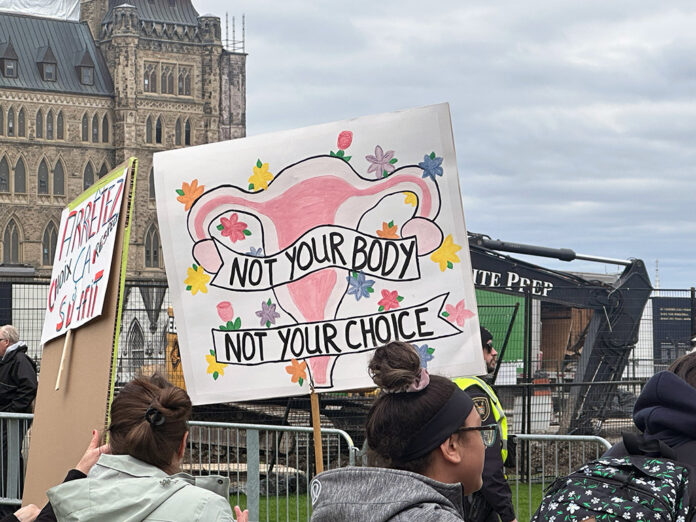 RALLY-FOR-CHOICE-ABORTION-FEATURE A colourful protest sign depicting a uterus and reading