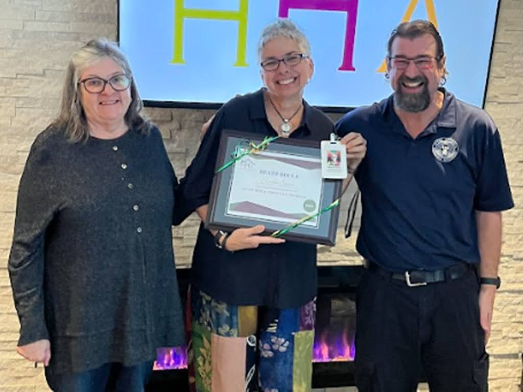 Three people together, with one holding a certificate.