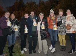 Group of people stand together in the night time holding candles.