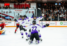 Minnesota Frost players celebrate with a player on the ice and other players gathering around.