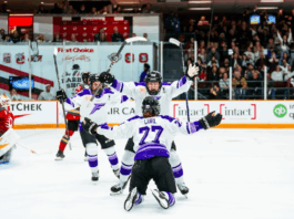 Minnesota Frost players celebrate with a player on the ice and other players gathering around.