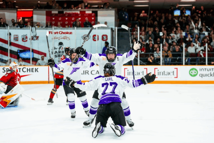 Frost Minnesota Frost players celebrate with a player on the ice and other players gathering around.
