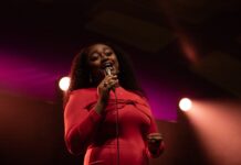 Review: Samara Joy is the parade that won’t be rained on at Ottawa Jazz Festival A person in a red dress sings passionately into a microphone on stage with red and orange lighting