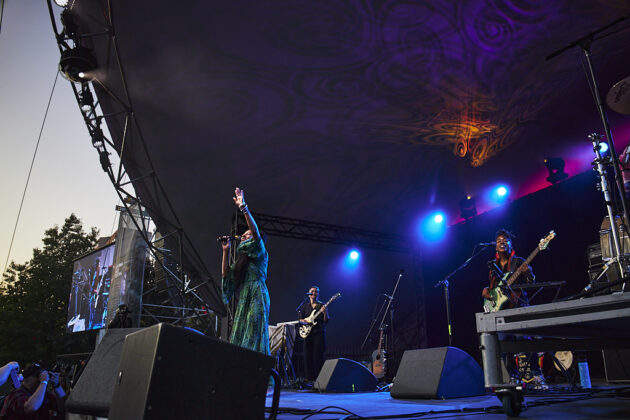 A woman performs on stage with a band.