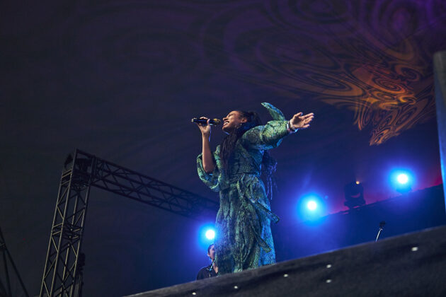 A woman sings passionately on stage, throwing her arm out as she dances.