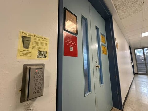 A door with a keypad against a white wall.