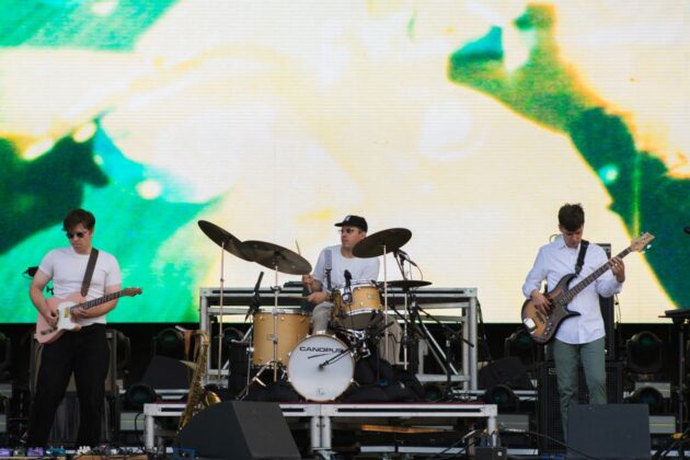 A band in white shirts performs on stage.