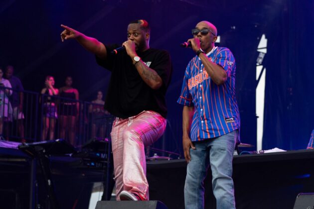 Two rappers perform on a colourful stage.