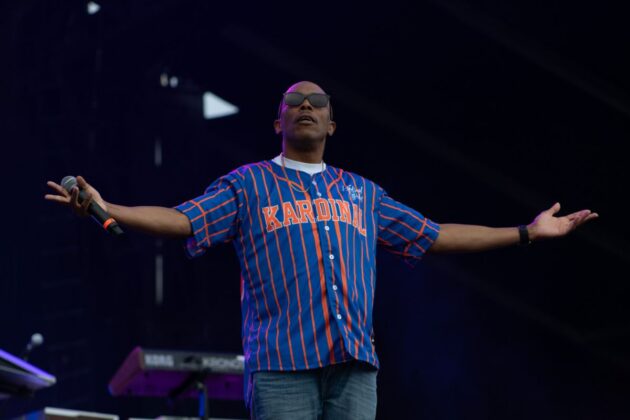 A rapper looks out, arms wide, over the crowd.